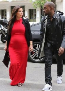 Long red dress for pregnant women with a black cardigan and a black clutch