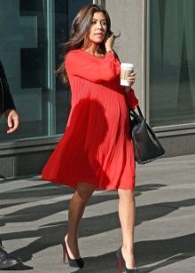 Red dress of a free cut for pregnant women in a combination with black shoes and a black bag