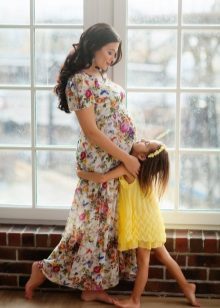 Photo shoot for a pregnant woman in a long dress with a floral print